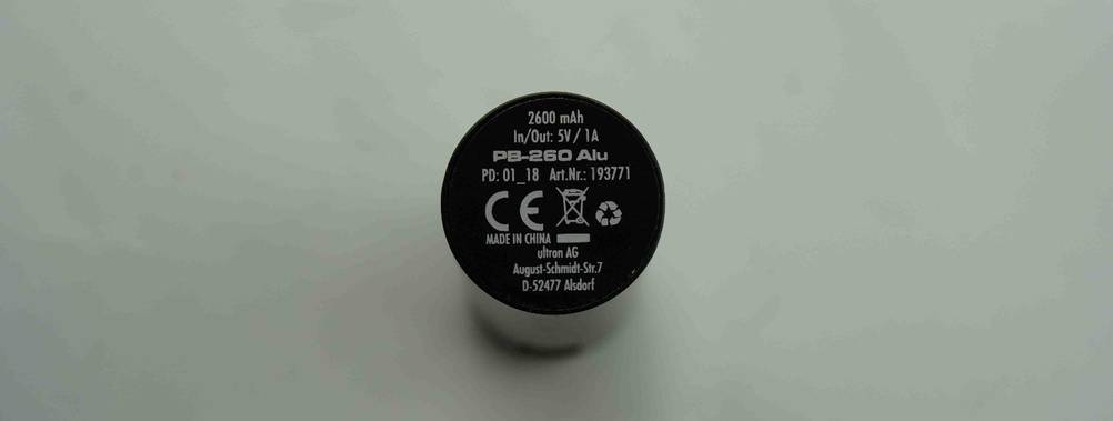 Schwarze, runde Mini-Powerbank im Test befindet sich mit Sicht auf die bedruckten Produktinformationen vor weißem Hintergrund.