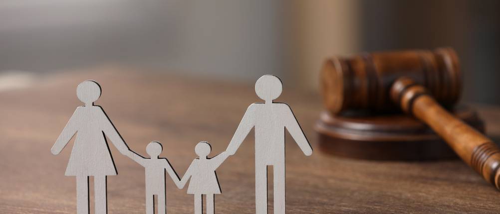 Rechtsschutzversicherungen im Vergleich: Figuren einer Familie bestehend aus Mutter, Vater und zwei Kindern, stehen auf einem Tisch neben einem Richterhammer.