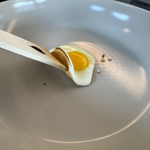 Spiegelei wird mit einem Holzspatel in der Redchef-Pfanne angehoben