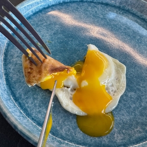 Mit Messer und Gabel das fertige Spiegelei anschneiden