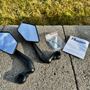 Die Reezer RS1 liegen neben der Anleitung und den Innensechskantschlüsseln auf einem Stein.