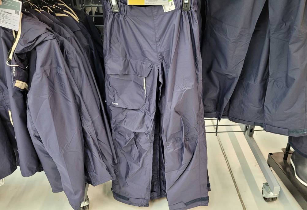 Mehrere Regenhose für Damen im Test: In einem Kaufhaus hängen mehrere Regenhose für Damen in der Farbe Dunkelblau auf den Regalen. 