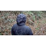 Eine Frau trägt die schwarze Helly Hansen Regenjacke mit aufgesetzter Kapuze und es regnet.