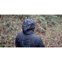 Eine Frau trägt die schwarze Helly Hansen Regenjacke mit aufgesetzter Kapuze und es regnet.