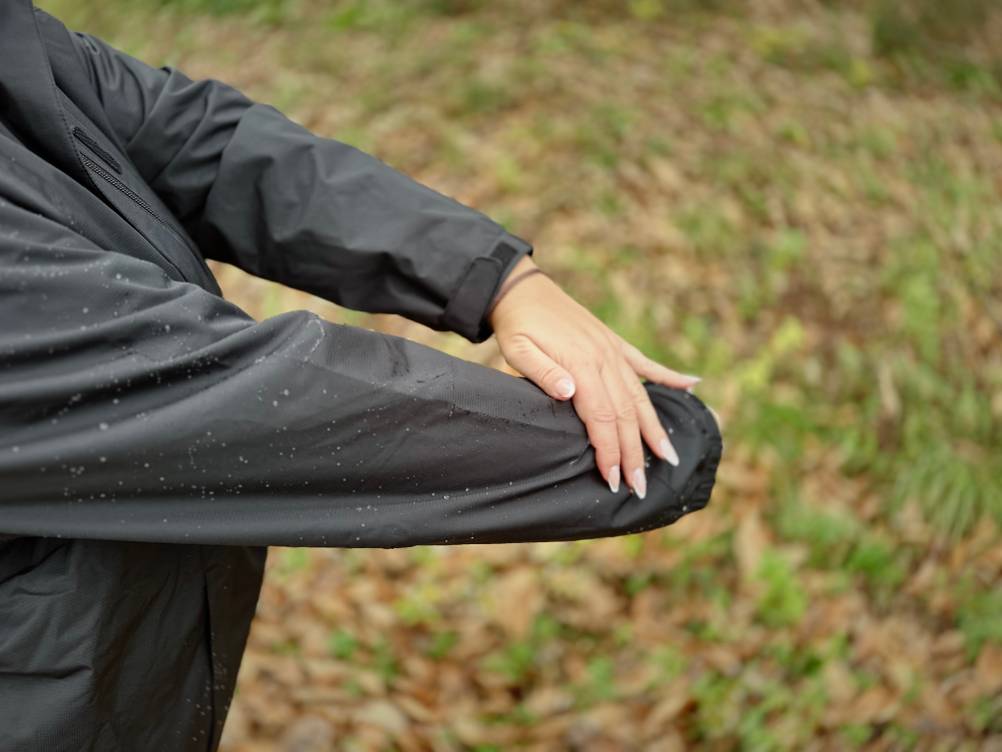 Regen perlt am Ärmel der schwarzen Vaude Damen-Regenjacke ab.
