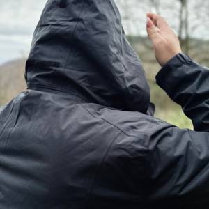 Die schwarze Vaude Damen-Regenjacke von hinten mit aufgesetzter Kapuze.