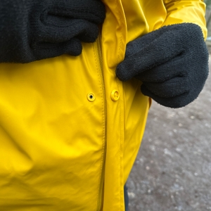 Nahaufnahme der gelben Druckknöpfe der Helly Hansen Moss Regenjacke. Sie sorgen für eine sichere Verschließung über dem Reißverschluss.