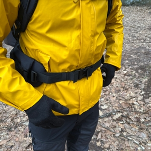 Eine Person trägt die Helly Hansen Moss Regenjacke mit einem Rucksack. Der Brustgurt liegt über der Jacke.