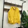 Eine gelbe Helly Hansen Moss Regenjacke hängt an einer Holzgarderobe