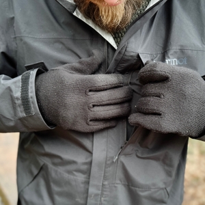Nahaufnahme der Brusttasche der Marmot Minimalist Regenjacke. Die Tasche wird mit Handschuhen geöffnet, der Reißverschluss ist wasserdicht.