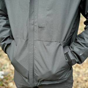 Eine Nahaufnahme der Marmot Minimalist Regenjacke zeigt die seitlichen Eingrifftaschen. Die Hände stecken lässig in den Taschen, während die Jacke im Outdoor-Einsatz getragen wird.