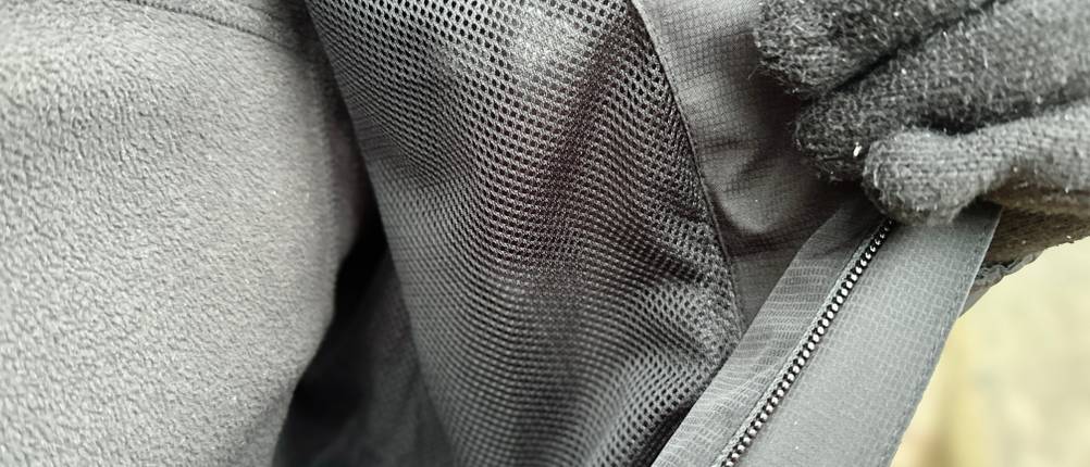 Das Innenfutter der Vaude Escape Light Regenjacke besteht aus atmungsaktivem Mesh-Material. Eine Person hält die Jacke leicht geöffnet.