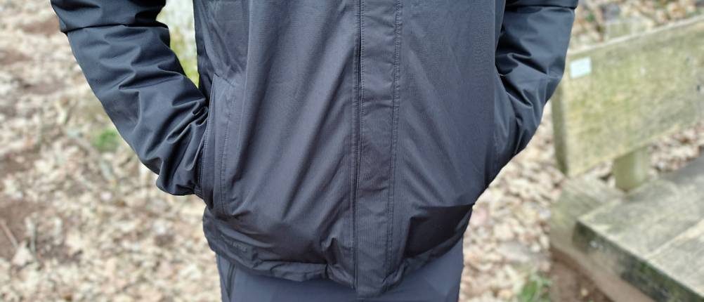 Die seitlichen Eingrifftaschen der Vaude Escape Light Regenjacke mit Reißverschlüssen. Eine Person steckt die Hände in die Taschen.