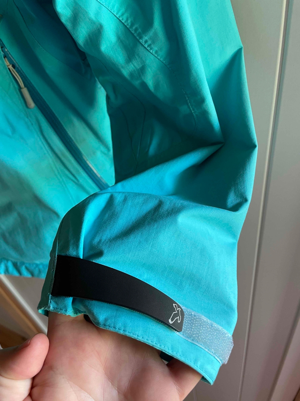 Armteil einer Regenjacke für Damen in Türkis.