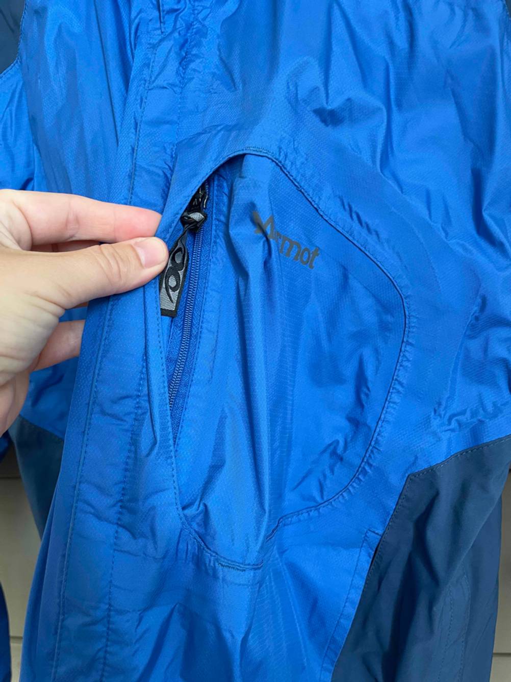 Regenjacke-Unisex-Test: Blaue Regenjackentasche mit Reißverschluss.