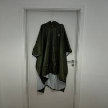 Der graue Anyoo-Regenponcho hängt auf einem Bügel am Türrahmen.