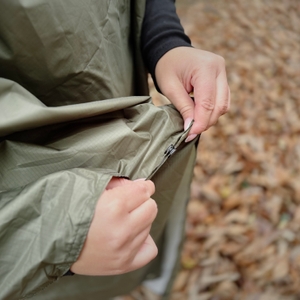Die Person zeigt die Nähte und die Qualität des Regenponchos Anyoo.