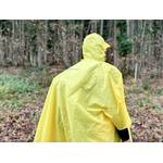 Eine Frau trägt einen gelben Regenponcho während einer Waldwanderung.