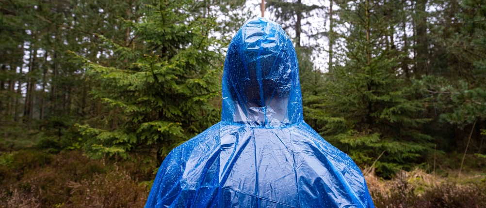 Rückansicht von Mann in blauem Regenponcho mit Kapuze.