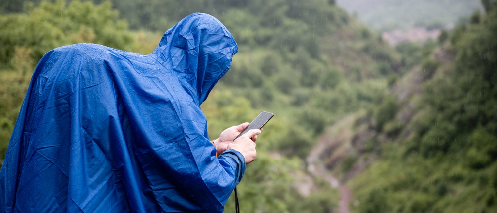 Ein Wanderer trägt einen blauen Regenponcho über einem großen Rucksack.