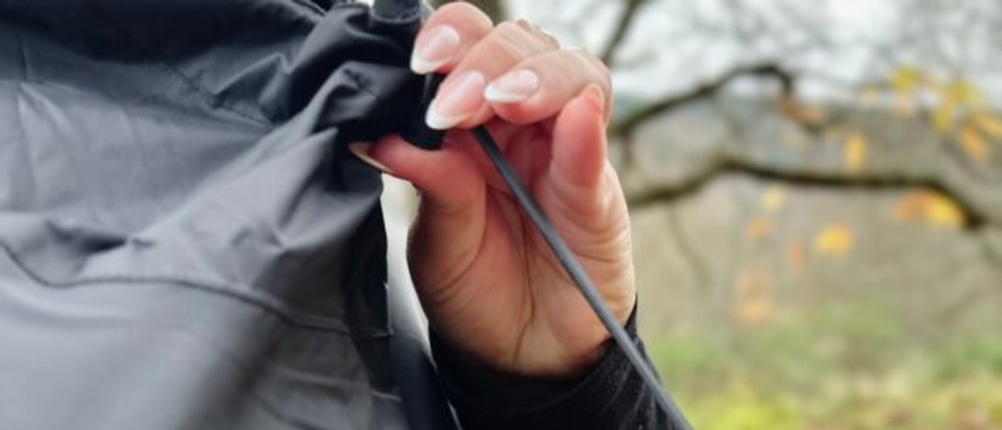 Die Person schließt die Kapuze mithilfe des Kordelzugs.