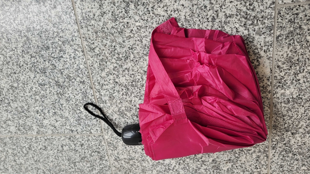 Regenschirm getestet: Ein Schirm liegt zusammengefaltet auf einer Marmorfliese.