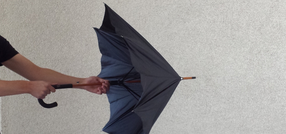 Getesteter Regenschirm in Blau wird per Hand geöffnet.