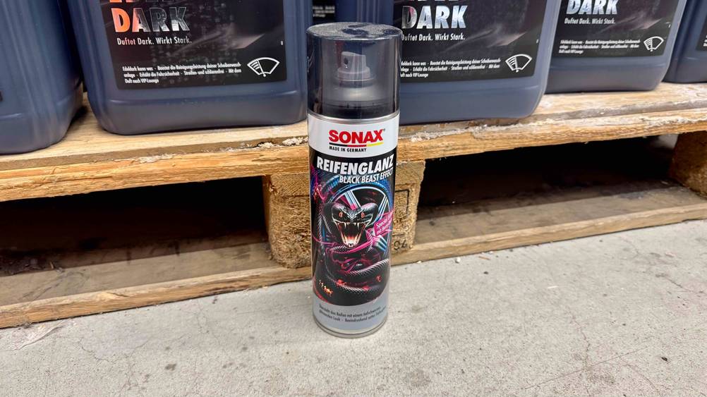 Eine Dose des Reifenglanz-Sprays im Test vor einer Palette mit Produkten auf dem Boden stehend.