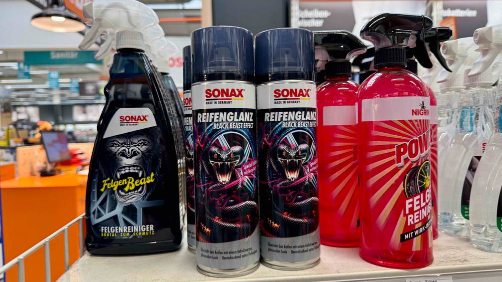 Mehrere Dosen des getesteten Reifenglanz-Sprays neben anderen Produkten in einem Verkaufsregal.