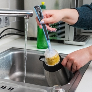 Eine Thermokanne wird mit einer Flaschenbürste im Spülbecken gereinigt.