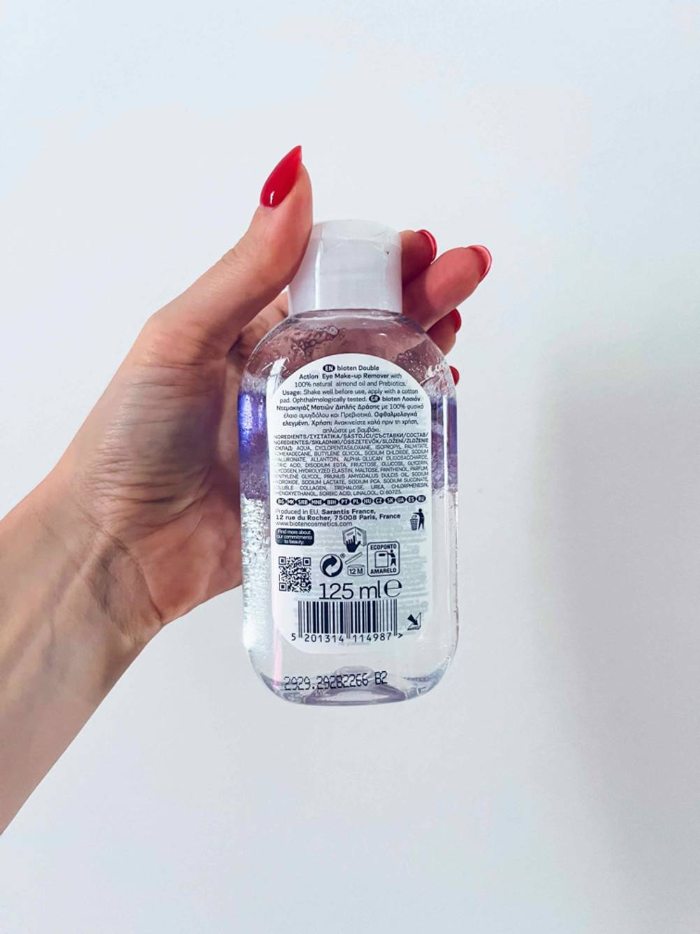 Reinigungsöl für das Gesicht im Test: Eine Hand hält eine Flasche mit der Rückseite nach vorne vor eine helle Fläche.