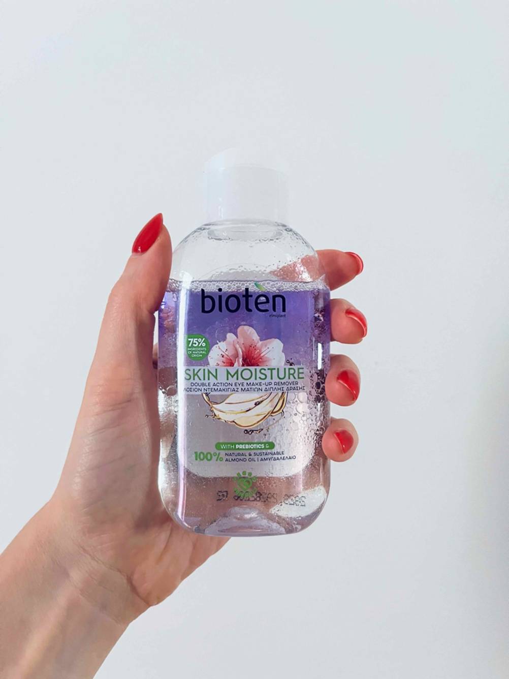 Eine Hand hält eine Flasche des getesteten Reinigungsöls für das Gesicht vor eine helle Wand.
