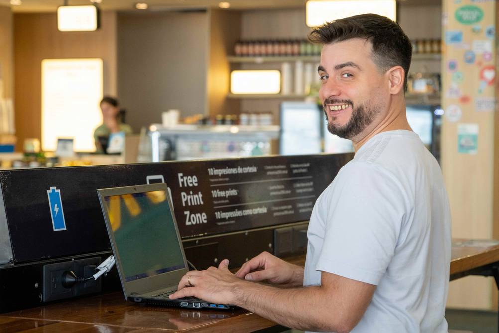 Reiseadapter-USA im Test: Ein Mann steht am Laptop in einer Zone, in der kostenlos geladen werden kann.