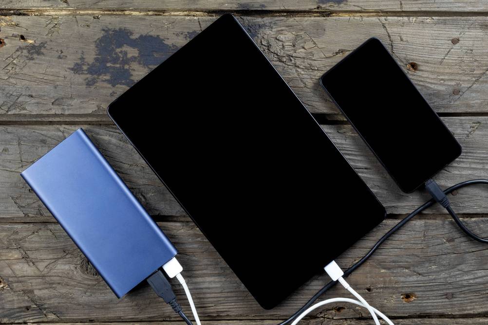Reiseadapter-USA-Test: Smartphone und Tablet an einer Powerbank auf einem Holz-Hintergrund.