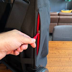 Eine Hand öffnet einen kleinen Reißverschluss an der Außenseite des Reisenthel DF7003.