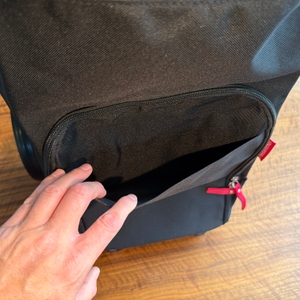 Eine Hand öffnet ein kleines Außenfach am Reisenthel DF7003.