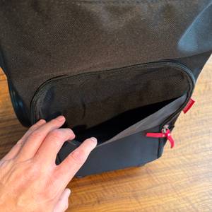 Eine Hand öffnet ein kleines Außenfach am Reisenthel DF7003.