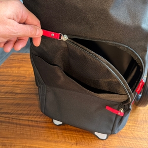 Eine Hand öffnet einen Reißverschluss an der Außenseite des Reisenthel DF7003.