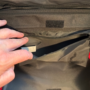 Eine Hand öffnet ein kleines Extrafach im Reisenthel DF7003.