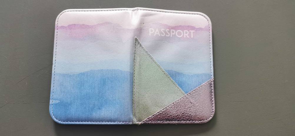 Getestet: Aufgeklappte Reisepasshülle mit Ansicht des Designs liegt auf dunkler Fläche.