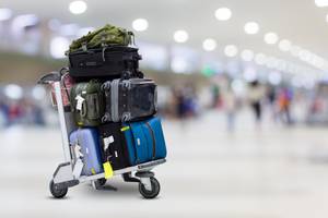 Reiserücktrittsversicherungen im Test: Ein Wagen mit mehreren Koffern steht an einem Flughafen.