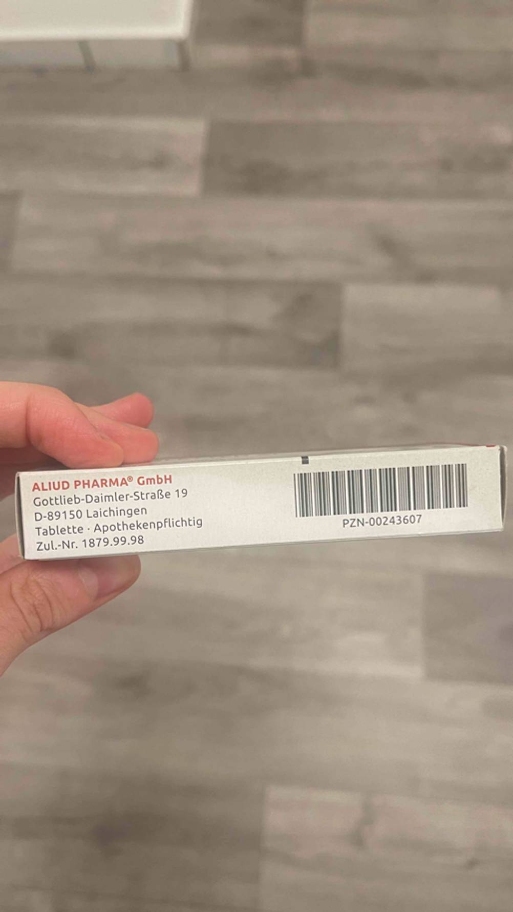 Reisetabletten getestet: Eine Hand hält die Verpackung inklusive der Herstellerinformationen vor einem braunen Hintergrund.