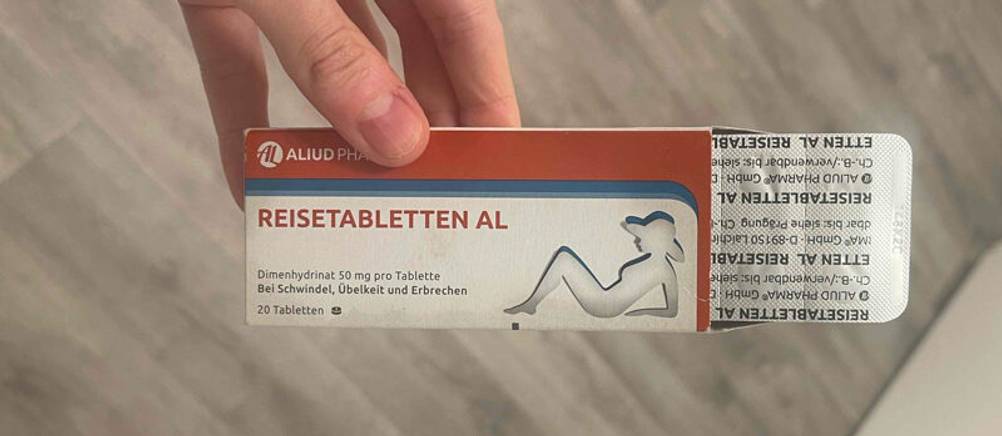 Reisetabletten im Test: Die weiß-rot-blaue Verpackung mit 20 Tabletten wird von einer Hand gehalten. Die Packung ist geöffnet und ein Blister schaut hervor.
