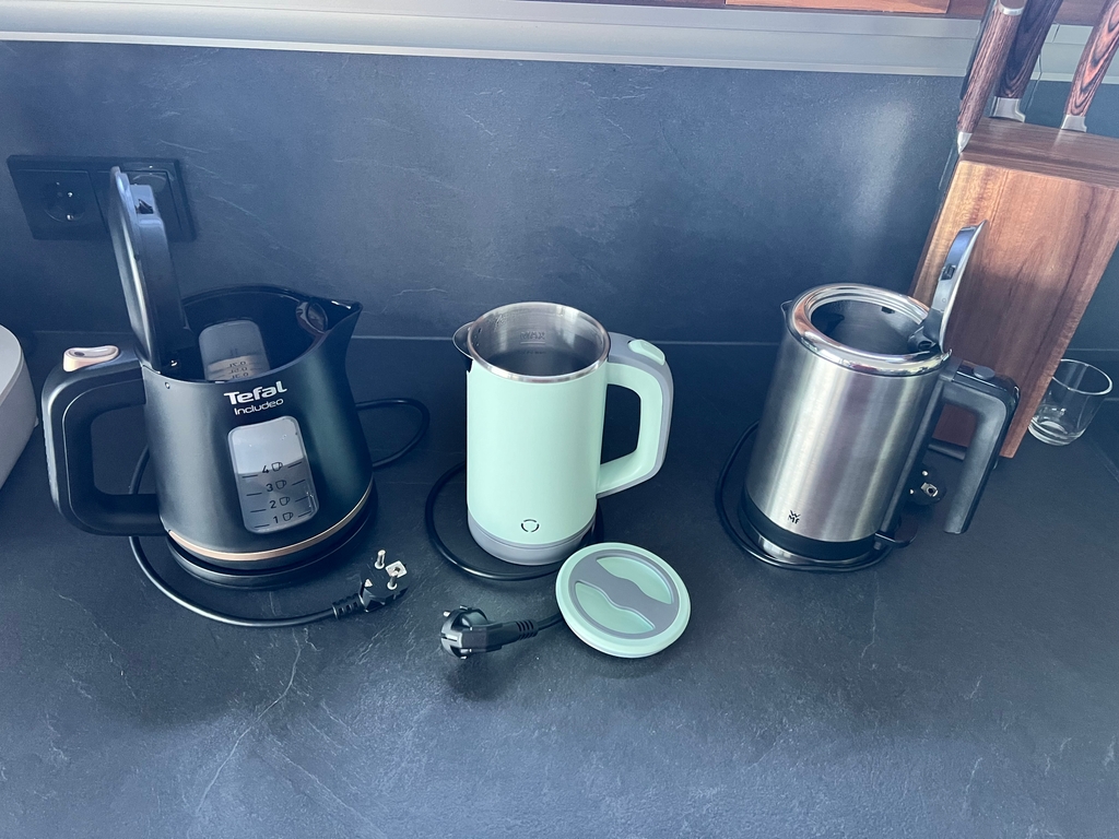 Drei Wasserkocher nebeneinander mit geöffneten Deckeln.