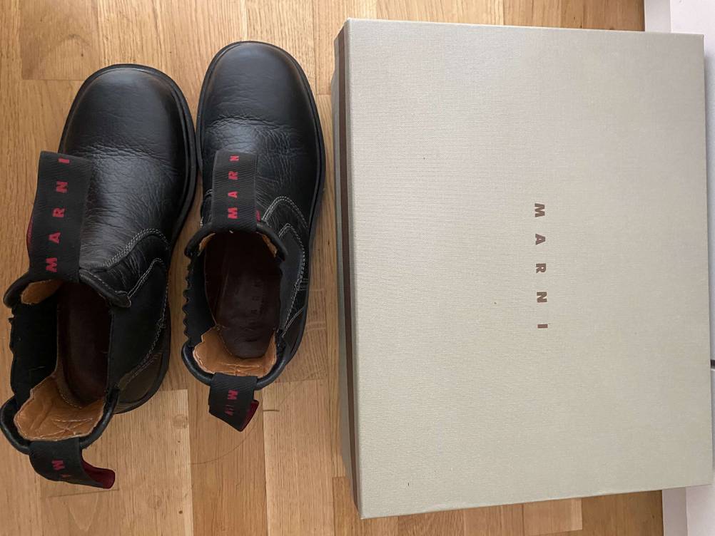 Neben dem Originalkarton steht ein Paar der getesteten Reitstiefel von oben.