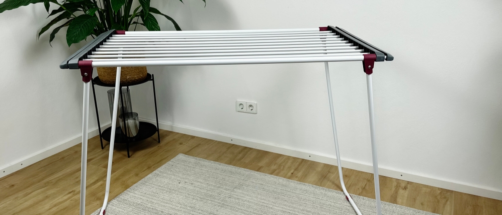 Der Relaxdays 10018866 steht aufgeklappt ohne ausgezogene Flügel auf einem Teppich. Die Leinen sind frei, keine Wäsche ist sichtbar.