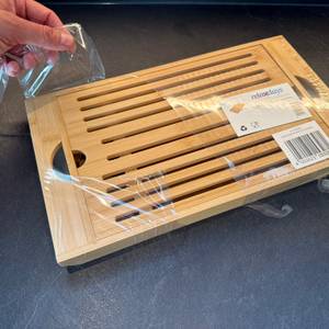 Eine Hand entfernt die Folie vom Relaxdays-Brotschneidebrett