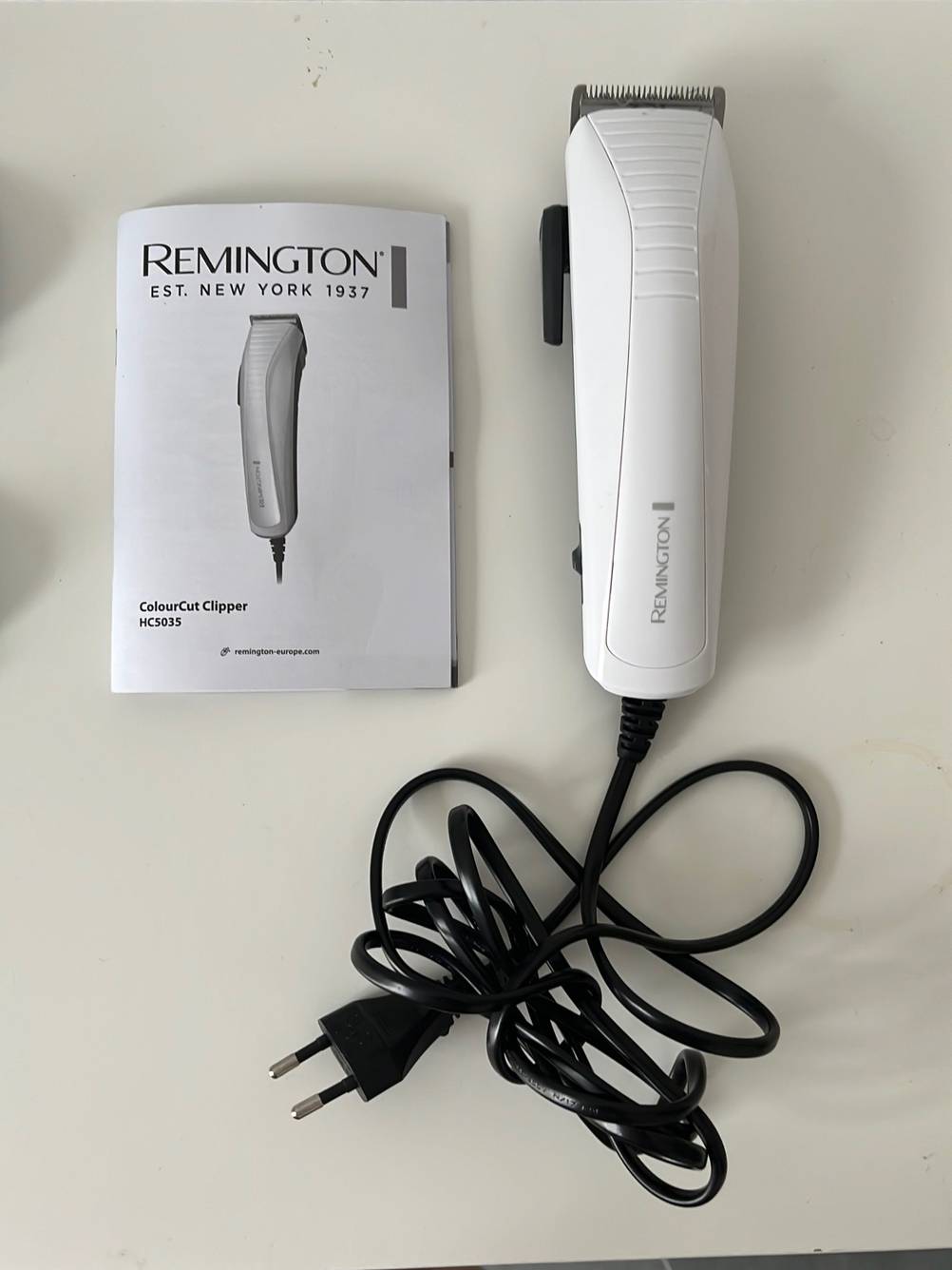 Remington Haarschneider im Test: Die Bedienungsanleitung liegt neben dem Gerät auf einer weißen Fläche.
