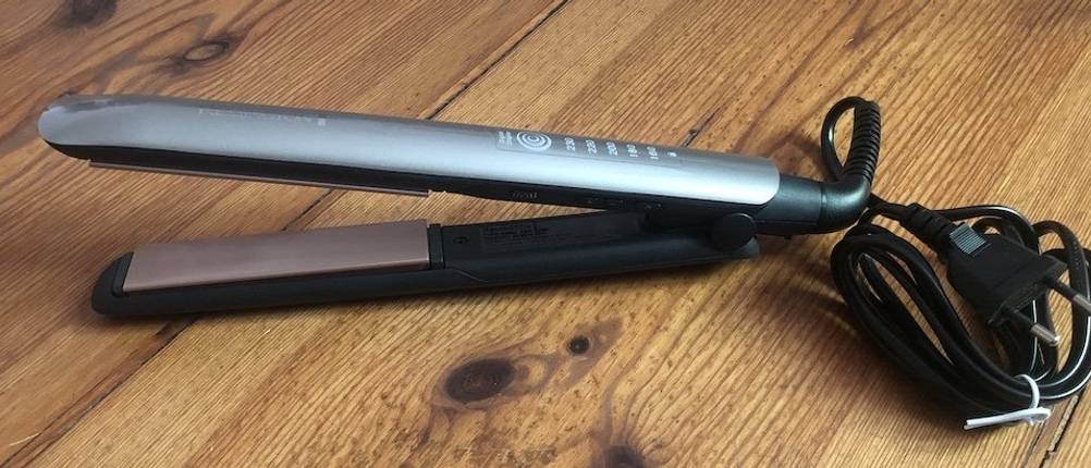 Das Keratin Therapy Glätteisen von Remington auf einem Holzuntergrund