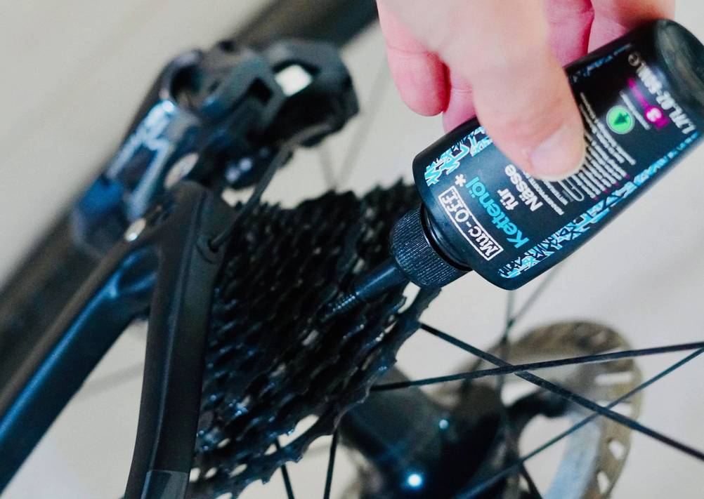 Die Kette eines Rennrads wird mit Kettenöl gepflegt.